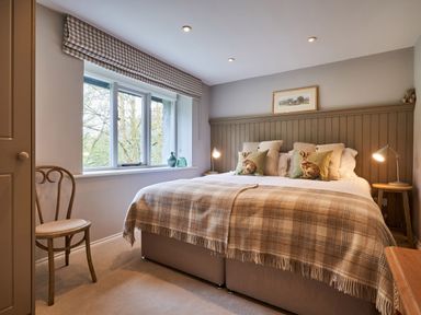 A bedroom with a double bed pillows with rabbits a wooden chair and a window at The Old Water Mill in Kendal