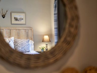A bedroom with a bed headboard pillows a table with a lamp and flowers and a framed picture on the wall at The Old Water Mill in Kendal
