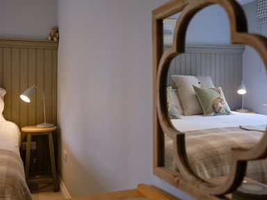 A bedroom with a bedside table lamp a teddy bear and patterned pillows on a bed at The Old Water Mill in Kendal