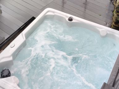 An outdoor hot tub with bubbling water on a wooden deck at The Old Water Mill in Kendal