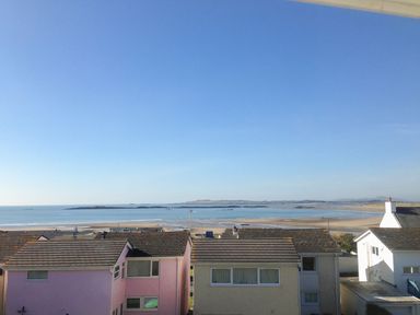 A coastal view with houses in the foreground a beach and sea with islands in the background at Sandy Toes in Rhosneigr
