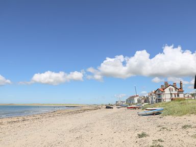 A sandy beach with boats and houses along the shore at Sandy Toes in Rhosneigr