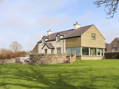 A house with stone walls and green grass in the yard at Dolwaenydd in Brynsiencyn