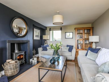 A living room with two sofas a coffee table with flowers a fireplace and a wooden bookshelf at Dolwaenydd in Brynsiencyn