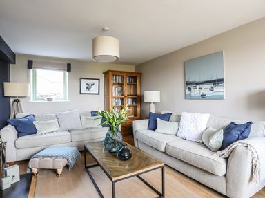 A living room with two sofas a wooden coffee table a wooden bookshelf and lamps at Dolwaenydd Brynsiencyn