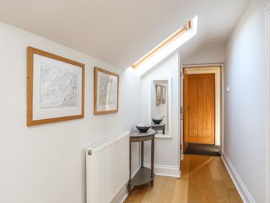 A hallway with wooden floor a small table with a bowl a mirror and two framed pictures on the wall at Dolwaenydd in Brynsiencyn