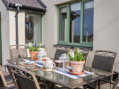 An outdoor patio dining table with chairs plants lanterns and a teapot at Dolwaenydd in Brynsiencyn