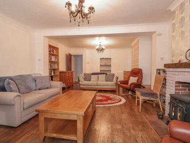 A living room with sofas chairs a wooden coffee table and a fireplace at Jobs Cottage in Snettisham