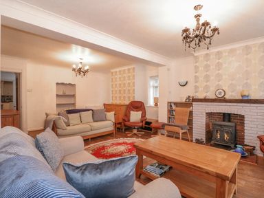 A living room with a fireplace wooden coffee table sofas an armchair and bookshelves at Job's Cottage in Snettisham