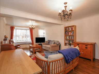 A living room with sofas chairs a coffee table bookshelf and a TV at Job's Cottage in Snettisham