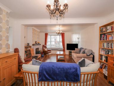 A living room with sofas a coffee table bookshelf and a television at Job's Cottage in Snettisham