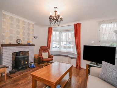 A living room with a fireplace leather chair and a television at Job's Cottage in Snettisham