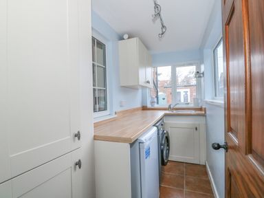 A utility room with a washing machine fridge cabinets and a sink at Job's Cottage in Snettisham