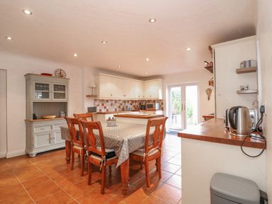 A kitchen with wooden dining table and chairs a cupboard and pantry at Job's Cottage in Snettisham