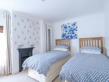 A bedroom with two single beds with blue patterned bedding and wooden headboards at Job's Cottage in Snettisham