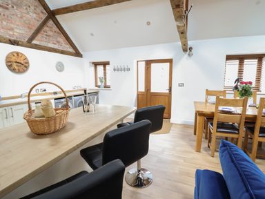 A kitchen and dining area with wooden table chairs and black bar stools at The Clockhouse in Llandyssil near Montgomery