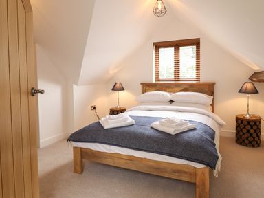 A bedroom with a wooden bed blue blanket and two bedside tables with lamps at The Clockhouse in Llandyssil near Montgomery