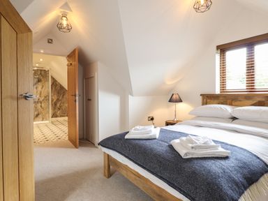 A bedroom with a wooden bed and bedside lamp next to a window at The Clockhouse in Llandyssil near Montgomery