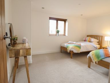 A bedroom with two single beds and wooden furniture at The Clockhouse in Llandyssil near Montgomery