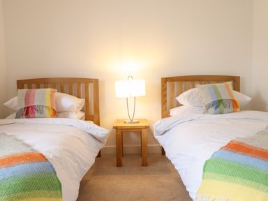 A bedroom with two wooden beds a nightstand and a lamp at The Clockhouse in Llandyssil near Montgomery