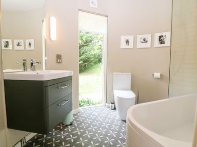 A bathroom with a sink cabinet toilet bathtub and window at Under Catswood in Elcombe near Stroud