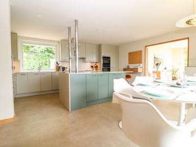 A kitchen with cabinets an island and a dining table with chairs at Under Catswood in Elcombe near Stroud
