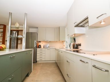 A kitchen with cabinets a refrigerator a countertop with a fruit bowl and appliances at Under Catswood in Elcombe near Stroud
