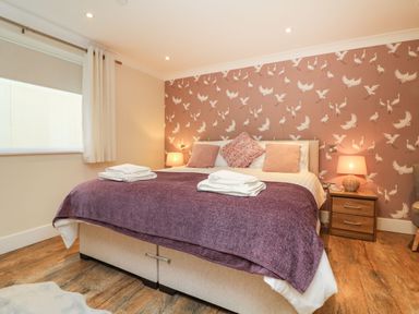 A bedroom with a double bed purple throw pillows and bedside lamps at The Lobster Pot in Westward Ho