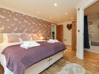 A bedroom with a double bed towels bedside lamp wooden floor and an adjacent bathroom at The Lobster Pot in Westward Ho