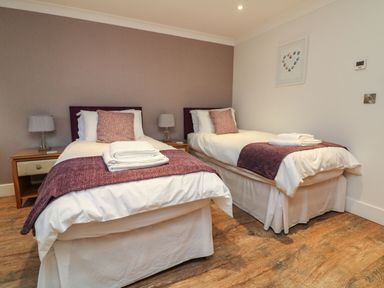 A bedroom with two single beds bedside tables and lamps at The Lobster Pot in Westward Ho