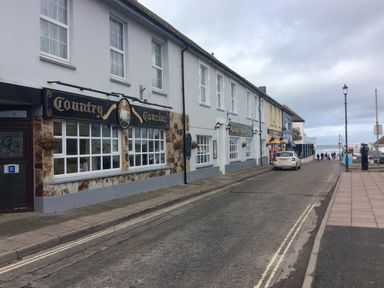 A street with shops and parked car by the seaside at The Lobster Pot in Westward Ho