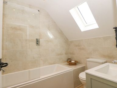 A bathroom with a bathtub, toilet, sink, and skylight at Haul A Gwynt in Criccieth