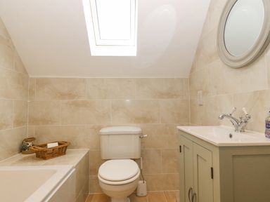 A bathroom with a toilet a sink a mirror a bathtub and a skylight at Haul A Gwynt in Criccieth
