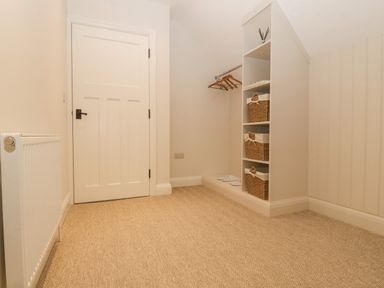 A room with a white door radiator and shelves with wicker baskets at Haul A Gwynt in Criccieth
