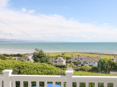 A coastal view with houses and green fields near the ocean at Haul A Gwynt in Criccieth