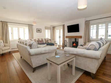 A living room with sofas a wood burning stove and a wall mounted television at Haul A Gwynt in Criccieth