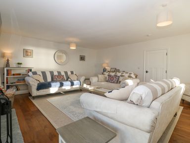 A living room with three sofas a coffee table a bookshelf lamps and a round mirror on the wall at Haul A Gwynt in Criccieth