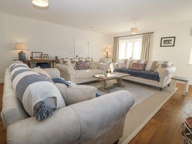 A living room with three sofas a coffee table lamps and framed pictures at Haul A Gwynt in Criccieth