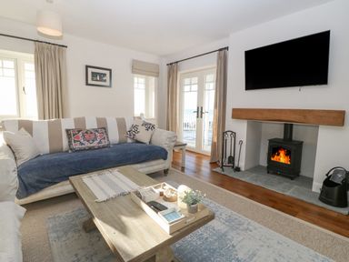 A living room with a sofa coffee table wood burning stove and television at Haul A Gwynt in Criccieth