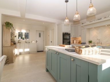A kitchen with blue island and hanging lights at Haul A Gwynt in Criccieth