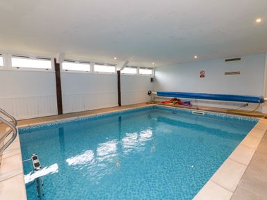 An indoor swimming pool with tiled floor and windows near the ceiling at Horseshoe Cottage in Hartland