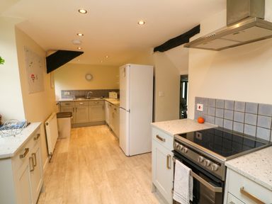 A kitchen with a stove dishwasher refrigerator and countertops at Horseshoe Cottage in Hartland