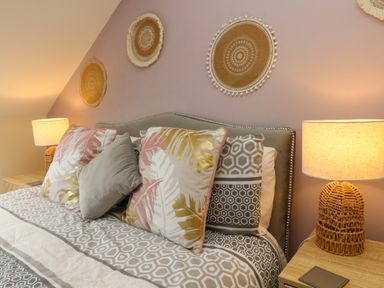 A bed with patterned pillows and lamps on wooden bedside tables at Horseshoe Cottage in Hartland