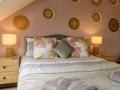 A bedroom with a bed with patterned pillows and bedside tables with lamps at Horseshoe Cottage in Hartland