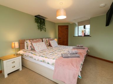 A bedroom with a double bed with pillows and folded towels bedside tables and a window at Horseshoe Cottage in Hartland