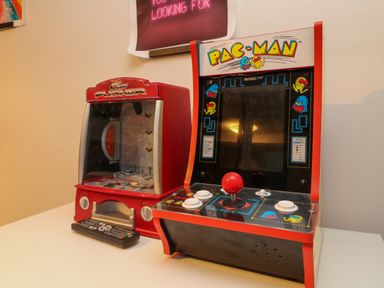 A table with a red coin pusher machine and a Pac-Man arcade game at Horseshoe Cottage in Hartland