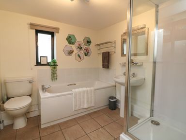 A bathroom with a toilet bathtub sink shower and wall decorations at Horseshoe Cottage in Hartland