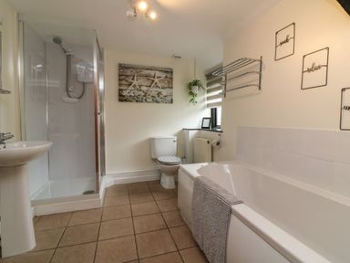 A bathroom with a bathtub a toilet a shower and a sink at Horseshoe Cottage in Hartland