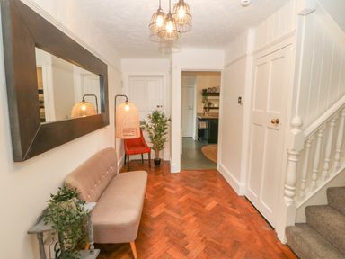 A hallway with a beige sofa and a large mirror on the wall next to a red chair and a plant at Afallon in Menai Bridge