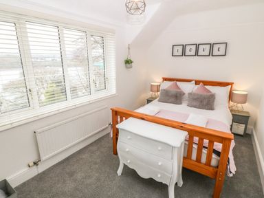 A bedroom with a wooden bed frame and white dresser at Afallon in Menai Bridge